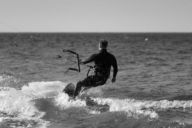 写真 空に照らして海でカイトボードをしている男