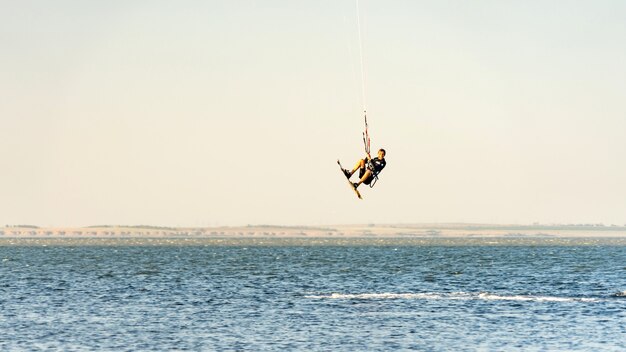 Man kitesurfer rijdt vliegerspringen. zwarte zeekust op zonnige dag. blagovesjenskaja. anapa, rusland.