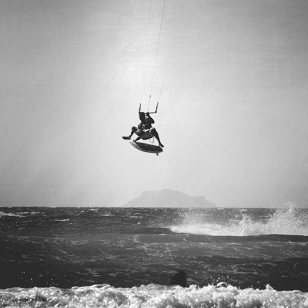 Man kitesurft over zee tegen de lucht