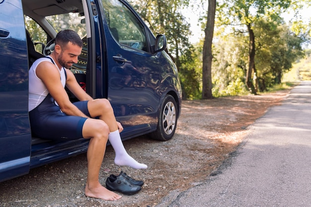 Man kleedt zich zittend op zijn busje om te gaan fietsen