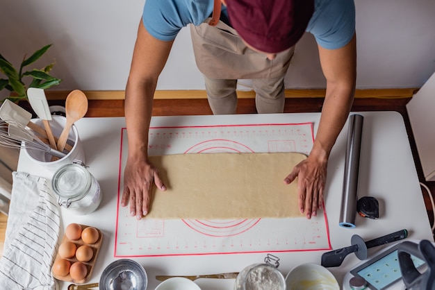 man kneading dough over a white table.