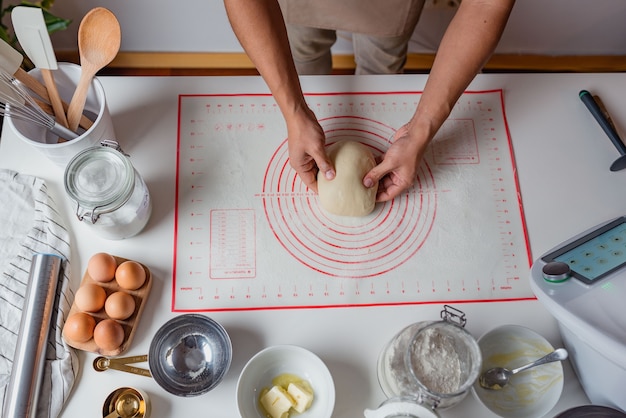 man kneading dough over a white table.