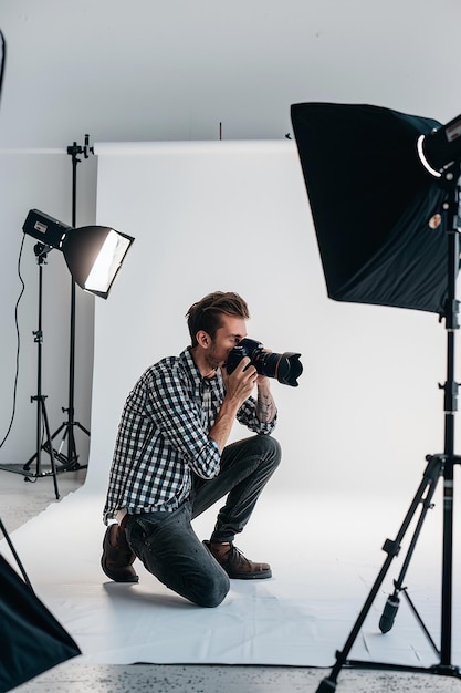 a man kneeling in front of a camera and wearing a shirt that says quot photography quot