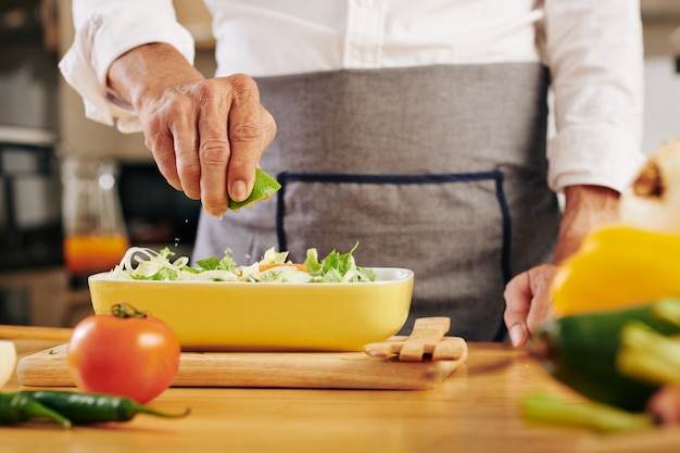 Man knijpen limoen in salade