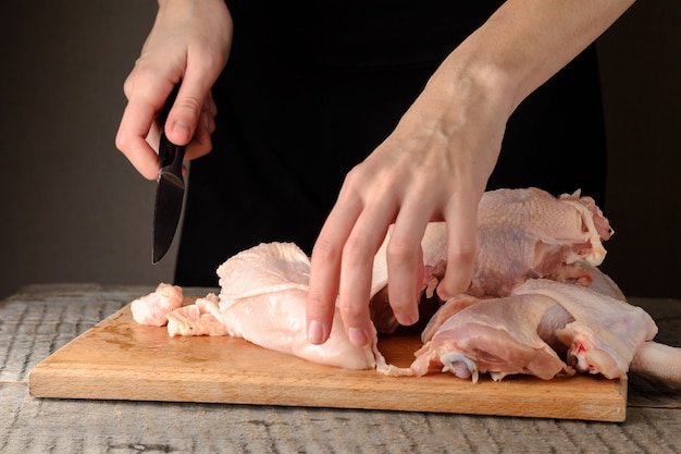 男は、生の鶏肉をまな板の上に細かく刻みます。