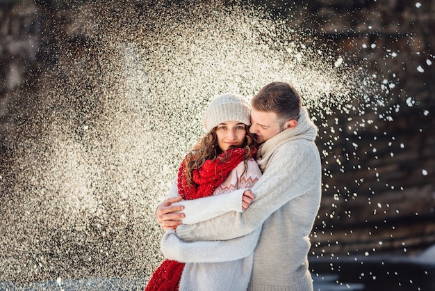 Foto man knuffelt een mooie vrouw tijdens een winterwandeling in de sneeuw