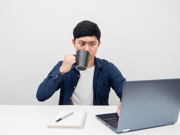 Man koffiekopje serieuze emotie drinken en kijken naar laptop op het bureau