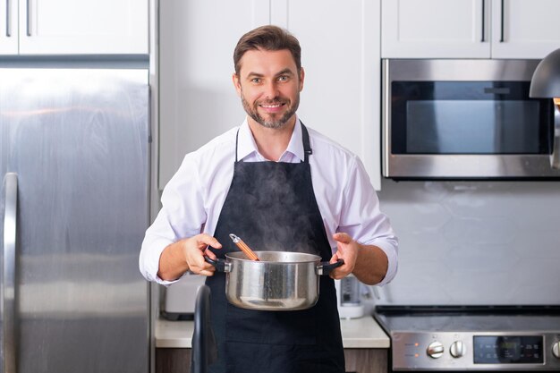 Man kok koken bij keuken chef-kok kok man bereidt een gerecht met voedsel in pan menu recept gezond