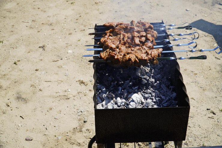 Man koken gemarineerde sjasliek lamsvlees grillen op metalen scheef