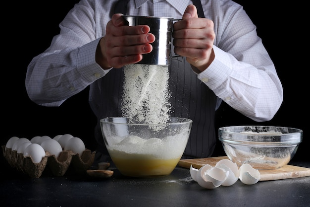 man koken Ziften van bloem in kom