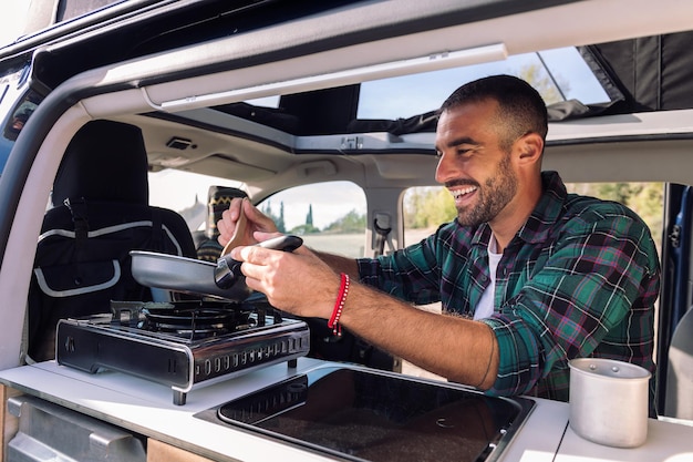 Man kookt met een koekenpan in zijn camper