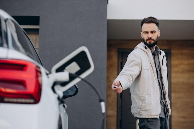 Man laadt elektrische auto bij het huis