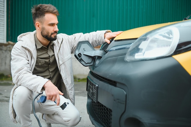 Man laadt elektrische auto bij het huis