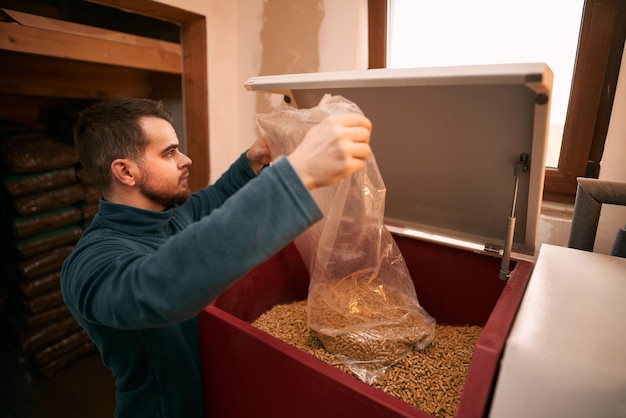 Man laadt houtpellets in de vaste brandstofketel Concept van verwarmingskachel die werkt met biobrandstoffen en zuinige verwarming