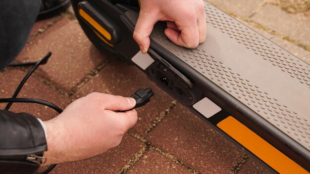 Man laadt zijn elektrische scooter met oplader op speciale parkeerplaats. close-up fotoshoot