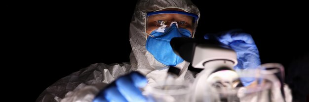 A man in a laboratory looks through a microscope