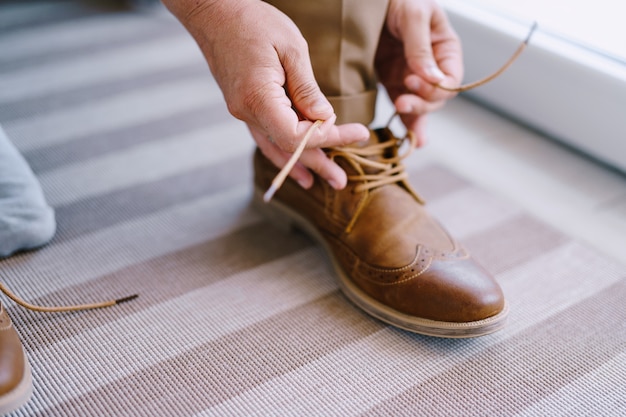 Man laces up brown brogues closeup