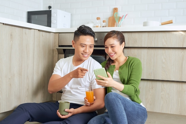 Man lachen met een meisje zittend op de vloer in de keuken met kopjes koffie en jus d'orange