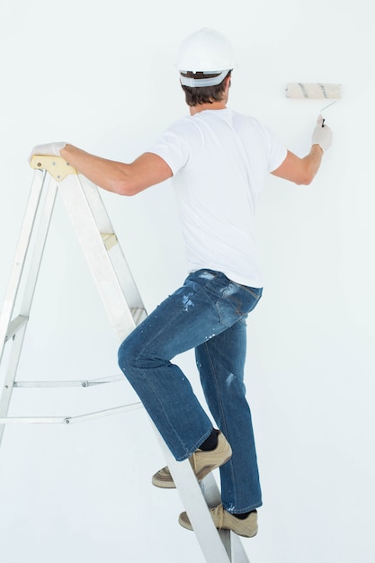 Man on ladder painting with roller