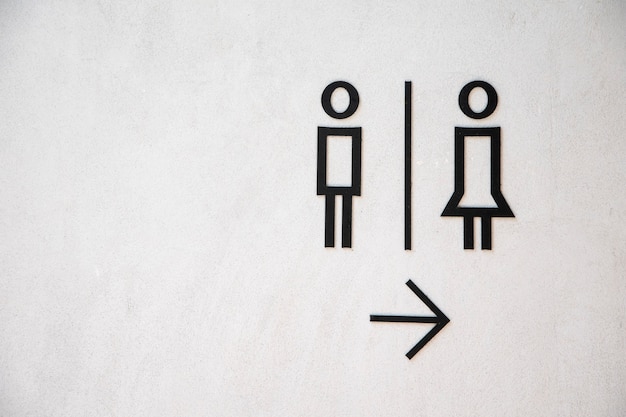 男と女のトイレは白いコンクリートの壁の背景にサインオンします。