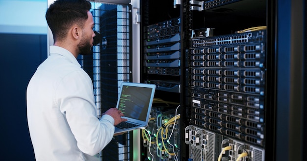 Man laptop and typing for programming in server room hardware and inspection for IT solution at company Person cybersecurity and assessment with computer coding and update software for system