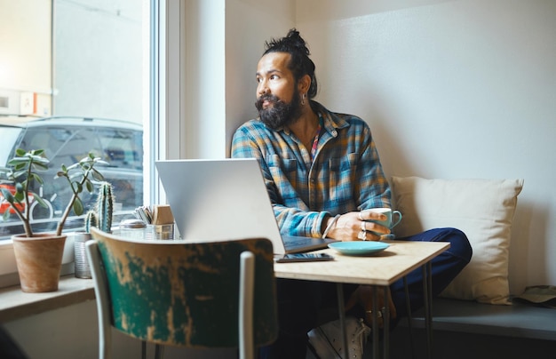 Man laptop en koffie etalage voor werken op afstand wifi en creatief denken online werken Ondernemer persoon denkt aan inspiratie of idee aan tafel voor sociale media netwerken en planning