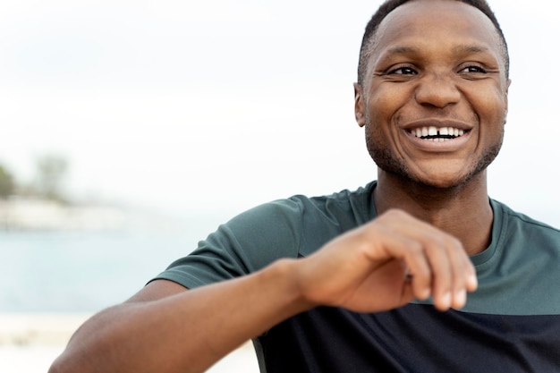 Man laughing out loud while standing at the seashore and preparing to the jogging