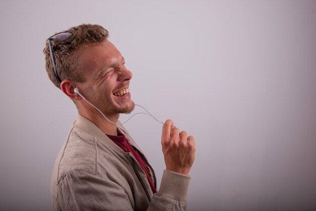 A man laughs while listening to an audio with his earphones studio shot with a white background