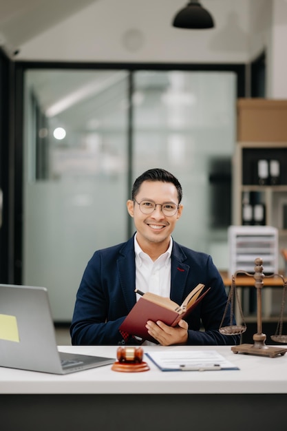 Photo man lawyer reading legal book with gavel on table in modern office justice and law attorney concept