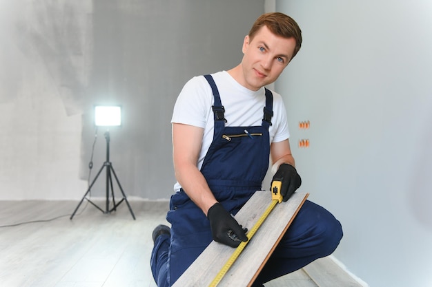 Man laying laminate flooring in construction concept