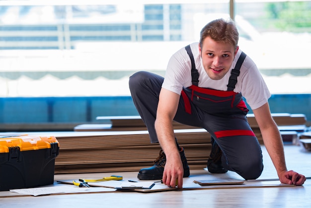 Man laying laminate flooring in construction 