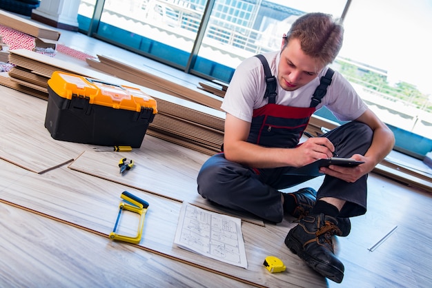 Man laying laminate flooring in construction 