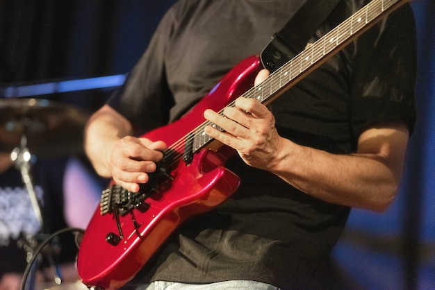 Man lead guitarist playing electrical guitar on concert stage.