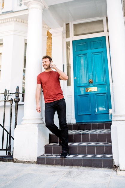 Photo man leaning in a blue door with mobile phone