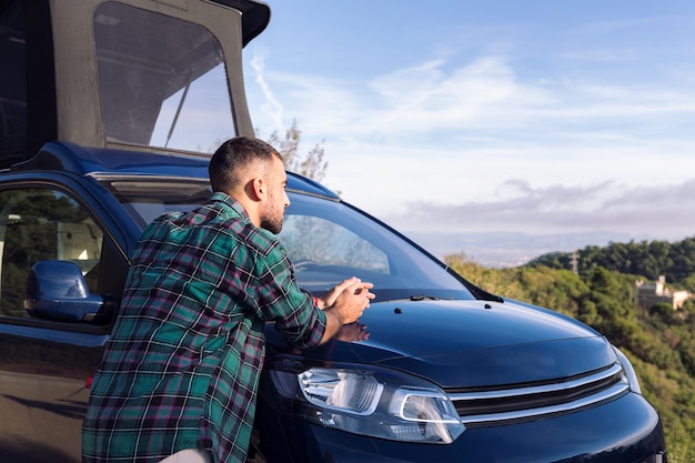 Man leaning on his camper van observing nature