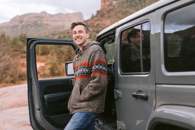 man leaning on sports car smiling happily