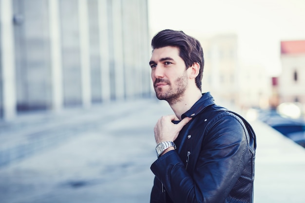 Man in leather jacket standing in city