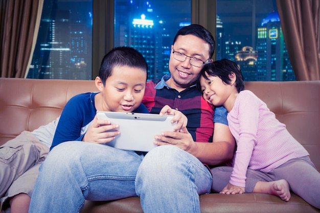 Man leert zijn kinderen hoe ze 's nachts een tablet moeten gebruiken