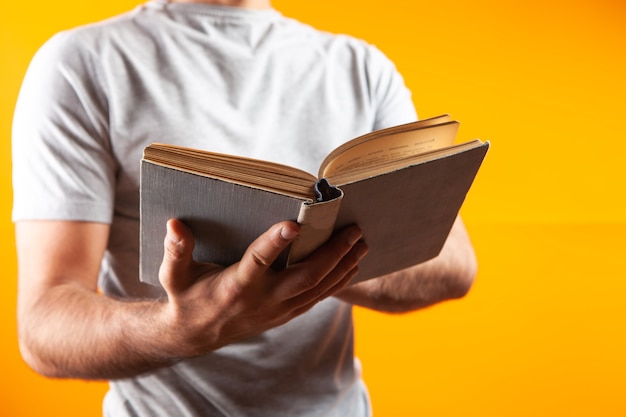 Man leest een boek terwijl hij op een oranje achtergrond staat