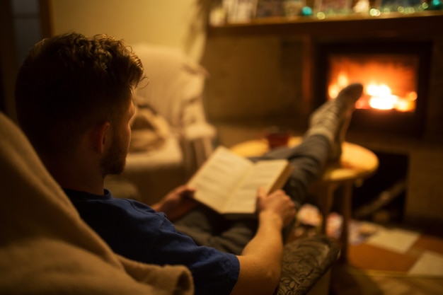 Man leest een boek voor een brandende open haard Gezellige wintersfeer