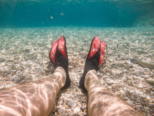 Man legs in flippers underwater copy space summer vacation