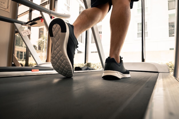 Man legs with sport shoes running on treadmill in fitness\
gym.