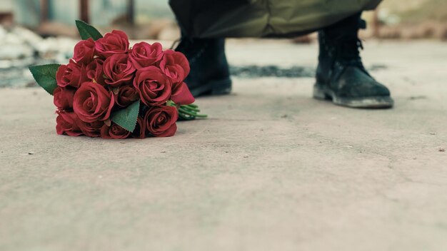 Man leunt bos rode bloemen op de grond