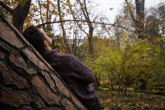 Foto man leunt op boomstam in het bos