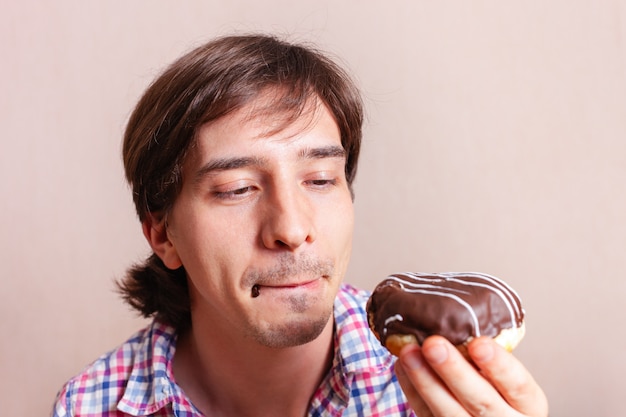 A man licks his lips on a chocolate donut.