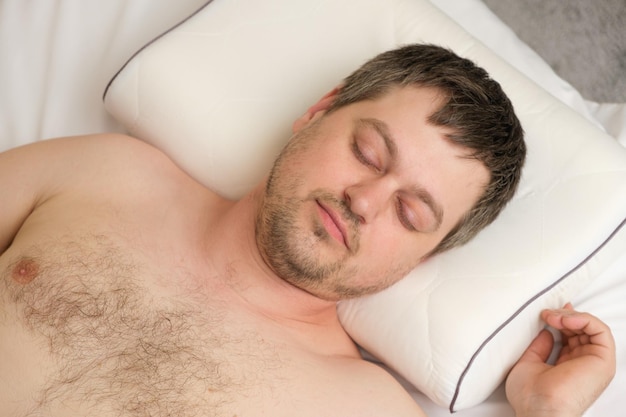 A man lies on an orthopedic pillow on his back