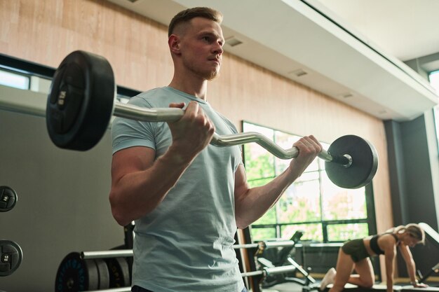 Foto uomo di sollevamento bilanciere in palestra