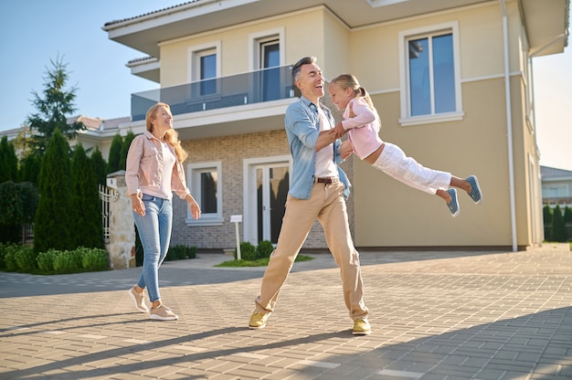 Man lifting daughter in his arms and woman