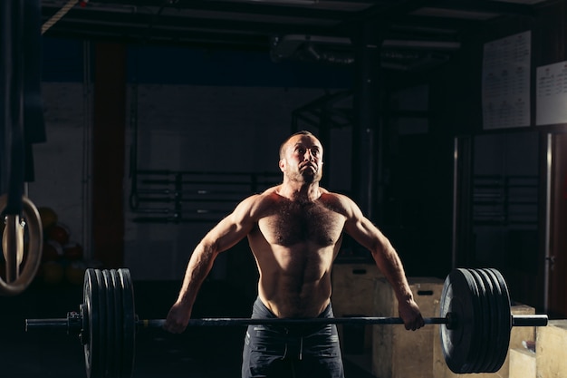 Uomo sollevamento pesi. allenamento uomo muscoloso in palestra facendo esercizi con bilanciere