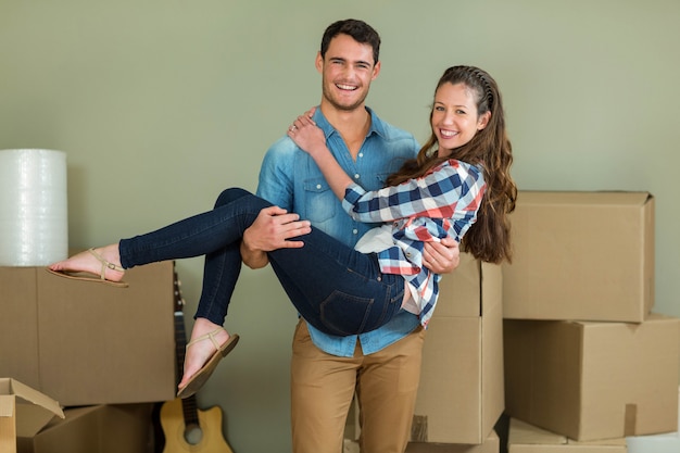 Man lifting woman in his arms in their new house